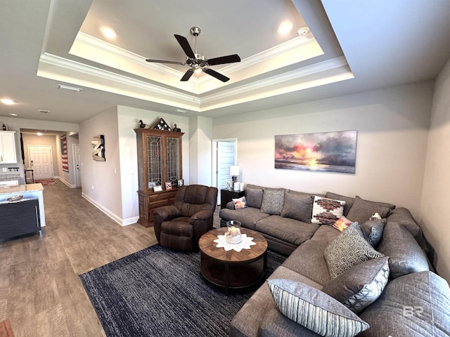 living area featuring a tray ceiling, wood finished floors, and crown molding