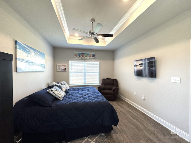 bedroom with baseboards, a raised ceiling, ceiling fan, wood finished floors, and crown molding