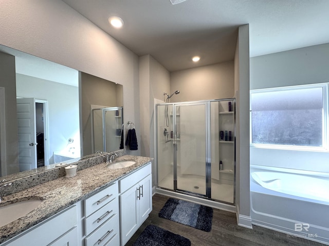 full bath with double vanity, wood finished floors, a stall shower, and a sink