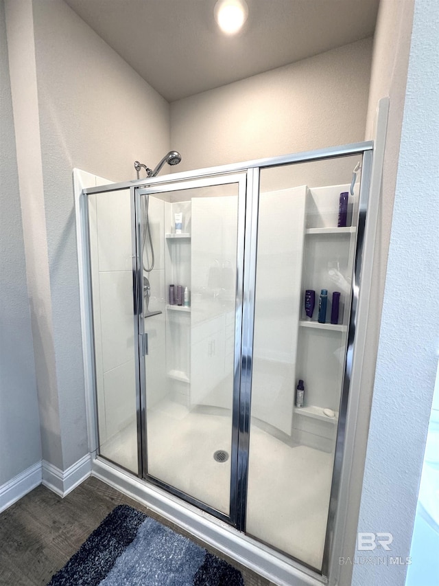 full bath featuring a stall shower, wood finished floors, and baseboards