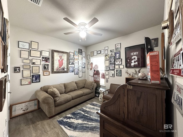 living room featuring visible vents, a textured ceiling, a ceiling fan, and wood finished floors