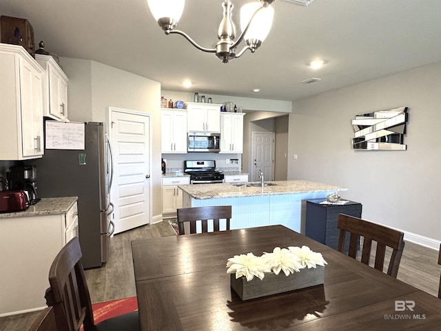 dining room featuring dark wood-type flooring, visible vents, a notable chandelier, and baseboards