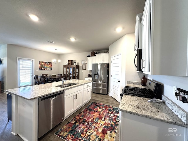 kitchen with a sink, white cabinets, appliances with stainless steel finishes, a center island with sink, and pendant lighting