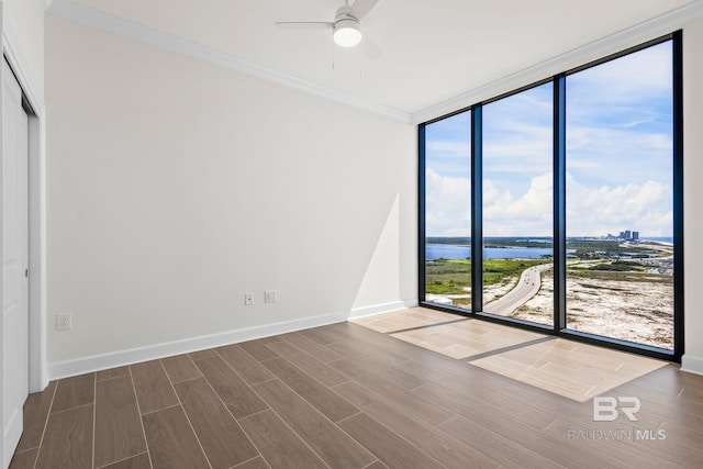 533 E Beach Blvd Unit 1905, Gulf Shores, AL 36542 - empty room featuring a wall of windows, a water view, wood finished floors, a ceiling fan, and baseboards