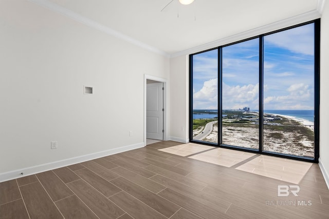 533 E Beach Blvd Unit 1905, Gulf Shores, AL 36542 - empty room with a wall of windows, a water view, ornamental molding, wood finished floors, and baseboards