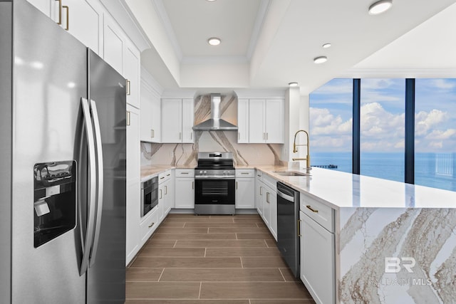 533 E Beach Blvd Unit 1905, Gulf Shores, AL 36542 - kitchen with stainless steel appliances, a sink, a tray ceiling, a peninsula, and wall chimney range hood