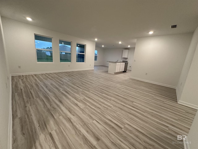 unfurnished living room featuring sink and light hardwood / wood-style floors