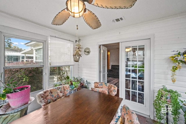 dining area featuring ceiling fan and wood walls