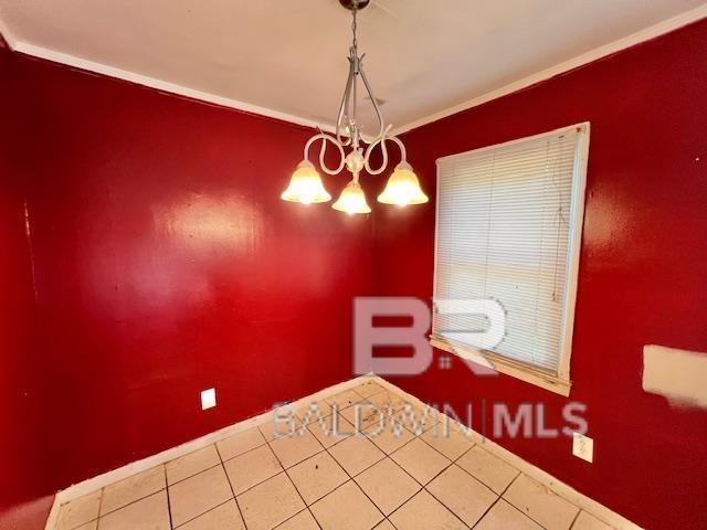 507 E Pine St, Atmore, AL 36502 - unfurnished bedroom featuring tile patterned floors, crown molding, baseboards, and a chandelier