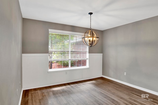 empty room with dark wood-type flooring and a notable chandelier