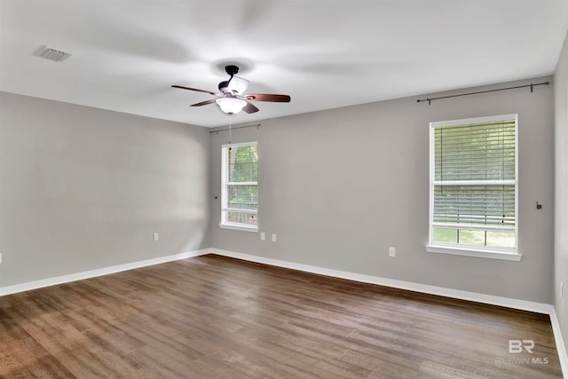 empty room featuring dark wood-type flooring, ceiling fan, and plenty of natural light