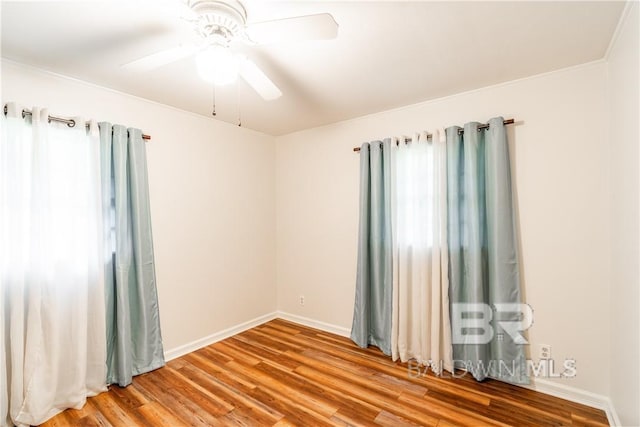 empty room with hardwood / wood-style floors, ceiling fan, a healthy amount of sunlight, and crown molding