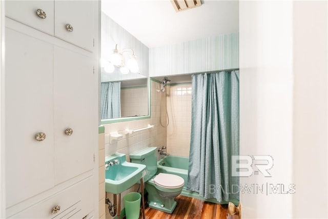 bathroom featuring backsplash, shower / bath combo with shower curtain, wood-type flooring, tile walls, and toilet