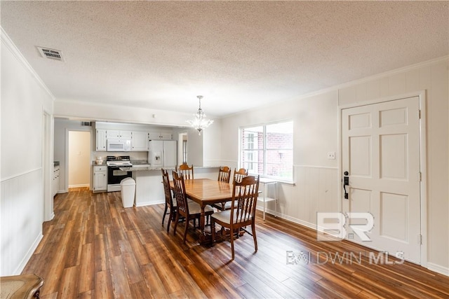 dining space with crown molding, dark hardwood / wood-style flooring, a textured ceiling, and an inviting chandelier