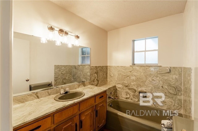 bathroom featuring a bathtub, vanity, a textured ceiling, and toilet