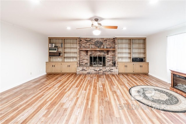 unfurnished living room featuring ceiling fan, built in features, light wood-type flooring, and a fireplace