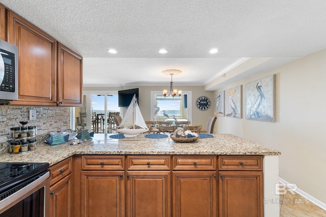 kitchen with hanging light fixtures, an inviting chandelier, a peninsula, and brown cabinets