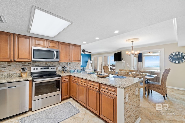 kitchen featuring brown cabinets, light stone countertops, stainless steel appliances, and backsplash