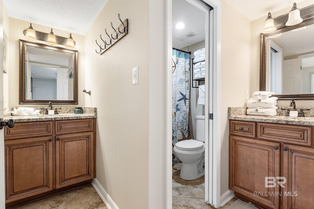 full bath featuring baseboards, visible vents, toilet, two vanities, and a sink