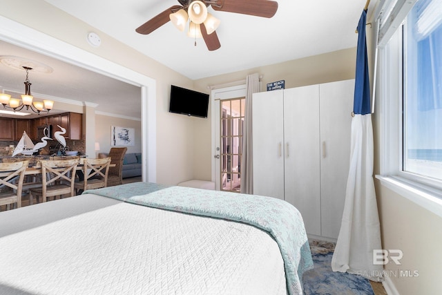 bedroom featuring ceiling fan with notable chandelier and crown molding