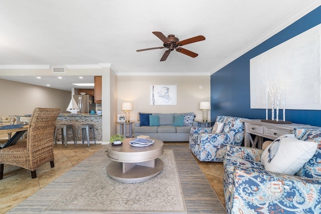 tiled living room featuring ornamental molding, visible vents, and a ceiling fan