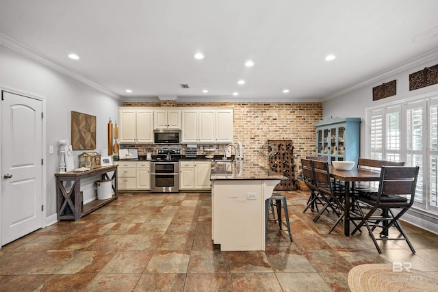 kitchen featuring stainless steel appliances, recessed lighting, ornamental molding, and a kitchen breakfast bar