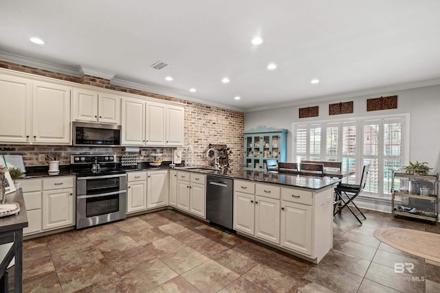 kitchen featuring crown molding, stainless steel appliances, visible vents, and a sink