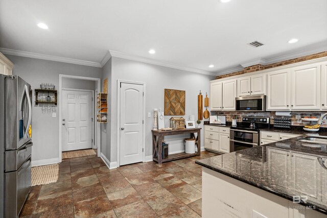 kitchen with appliances with stainless steel finishes, a sink, baseboards, backsplash, and visible vents