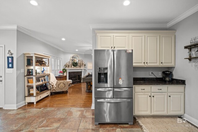 kitchen with ornamental molding, cream cabinetry, stainless steel fridge with ice dispenser, and a fireplace