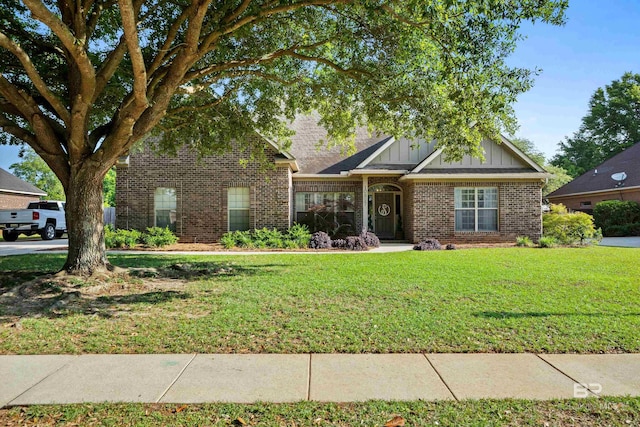 view of front of property with board and batten siding, a front yard, and brick siding