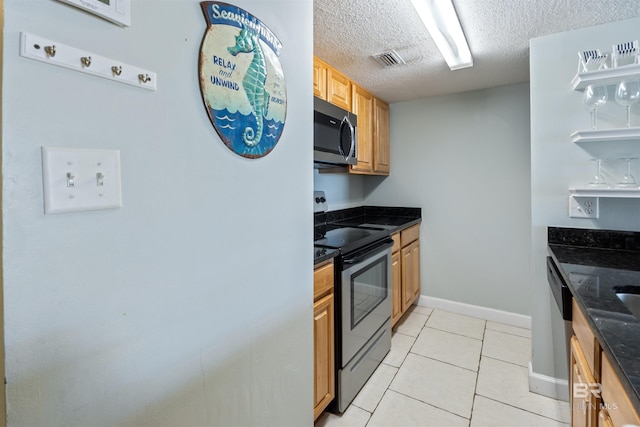23044 Perdido Beach Blvd Unit 338, Orange Beach, AL 36561 - kitchen with appliances with stainless steel finishes, a textured ceiling, dark stone counters, light tile patterned floors, and baseboards