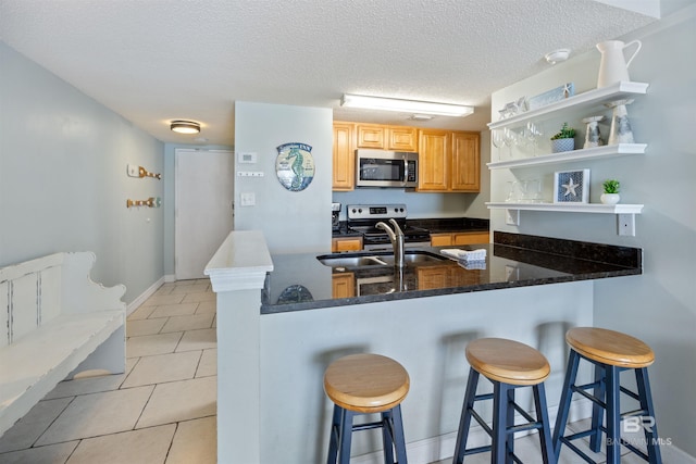 23044 Perdido Beach Blvd Unit 338, Orange Beach, AL 36561 - kitchen featuring appliances with stainless steel finishes, open shelves, a sink, light tile patterned flooring, and a breakfast bar