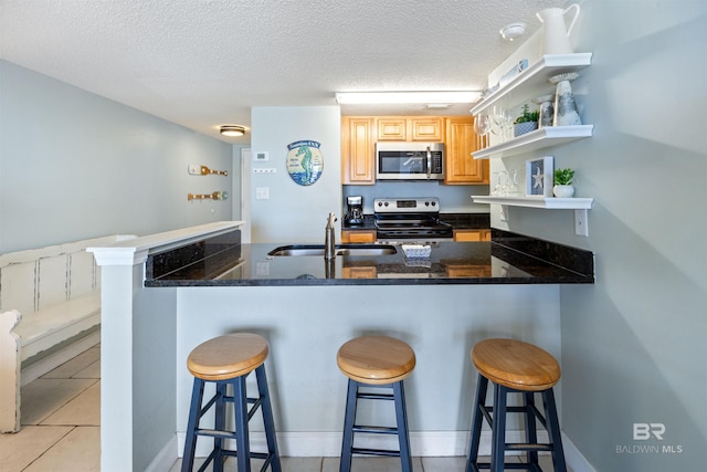 23044 Perdido Beach Blvd Unit 338, Orange Beach, AL 36561 - kitchen featuring appliances with stainless steel finishes, open shelves, a sink, a breakfast bar area, and light brown cabinets
