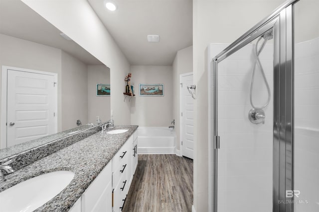 9365 Eiland Dr, Foley, AL 36535 - bathroom featuring wood finished floors, a stall shower, a bath, double vanity, and baseboards
