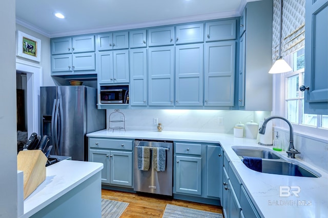 kitchen featuring tasteful backsplash, ornamental molding, wood-type flooring, appliances with stainless steel finishes, and sink