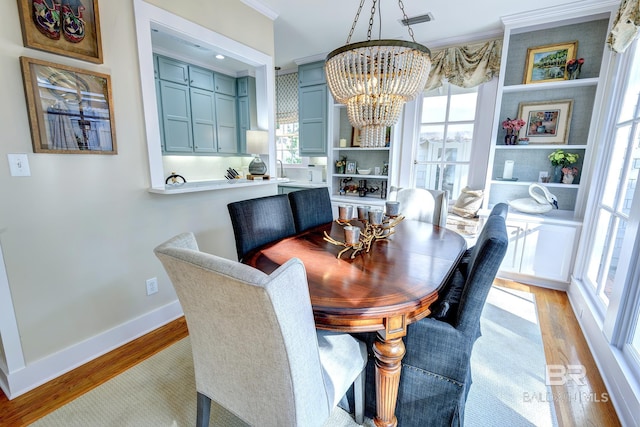 dining room with a notable chandelier, light hardwood / wood-style flooring, and crown molding