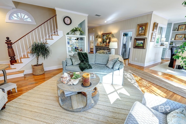 living room with wood-type flooring and ornamental molding