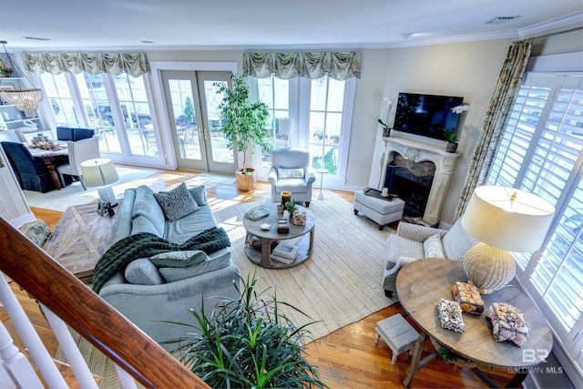 living room with hardwood / wood-style flooring, ornamental molding, a high end fireplace, and french doors