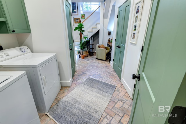 clothes washing area featuring washing machine and clothes dryer and cabinets