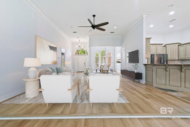 unfurnished living room with ornamental molding, light wood-type flooring, ceiling fan, and decorative columns