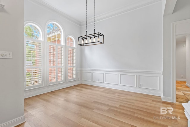 unfurnished dining area with light hardwood / wood-style flooring, crown molding, and a chandelier