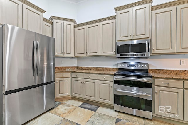 kitchen featuring appliances with stainless steel finishes, crown molding, and dark stone countertops