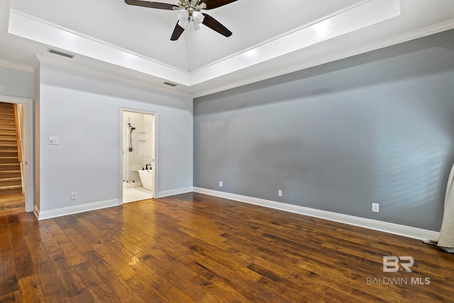 unfurnished bedroom featuring dark hardwood / wood-style floors, a raised ceiling, ensuite bathroom, crown molding, and ceiling fan