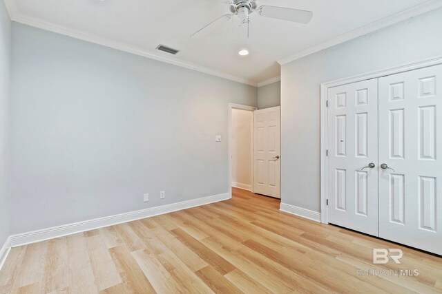 unfurnished bedroom with light hardwood / wood-style floors, ornamental molding, ceiling fan, and a closet