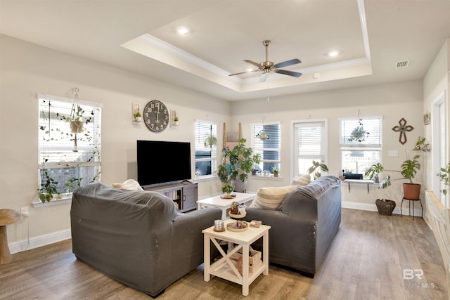 living room with hardwood / wood-style flooring, a raised ceiling, ceiling fan, and crown molding