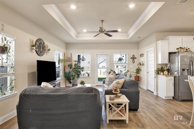 living room featuring a tray ceiling, ceiling fan, light hardwood / wood-style floors, and ornamental molding