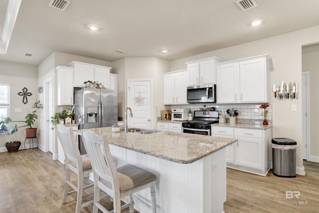 kitchen with light stone countertops, sink, white cabinetry, and stainless steel appliances