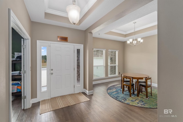 entrance foyer featuring plenty of natural light, a raised ceiling, crown molding, and a chandelier