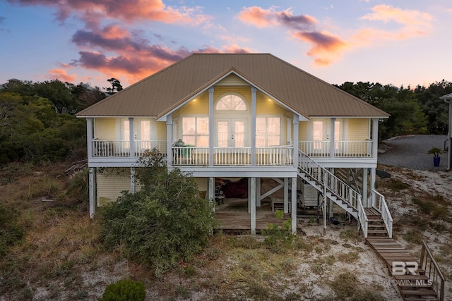 back house at dusk featuring a porch and french doors