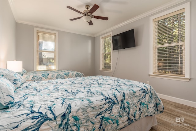 bedroom with multiple windows, ceiling fan, light wood-type flooring, and ornamental molding